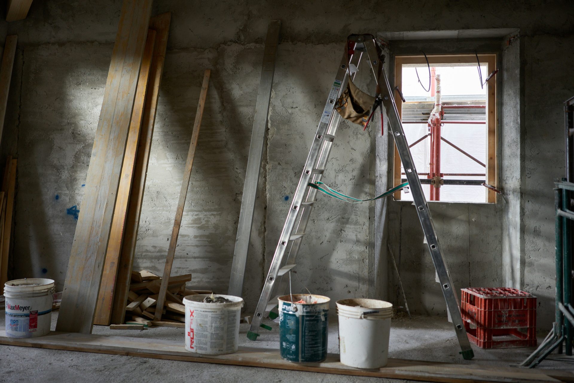 Una escalera y cubos de pintura en una habitación en construcción.